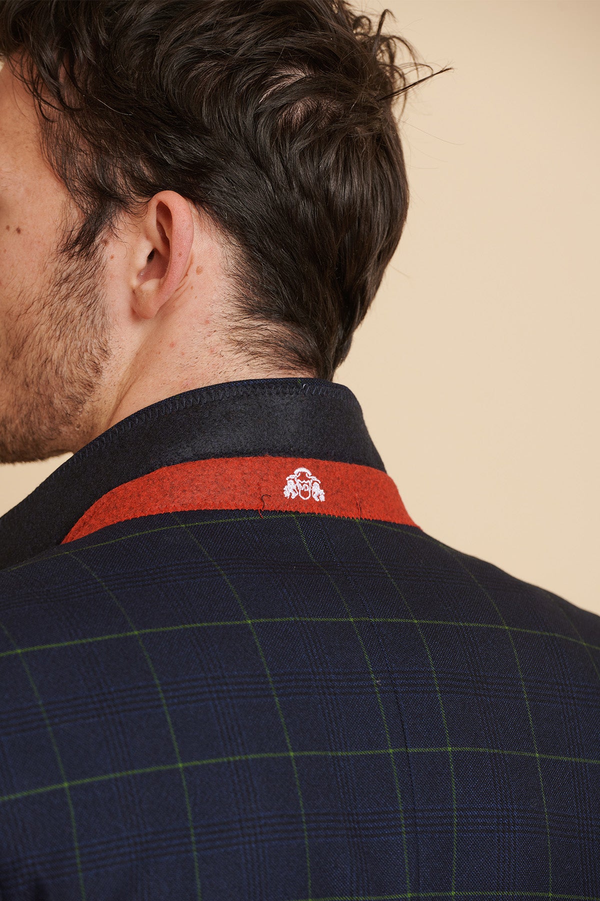 Close-up of a man wearing the Marc Darcy Everton Collection | Beto In EDINSON Navy Green Check Two Piece Suit, showcasing the back collar with red accents and an embroidered crest. The slim tailored fit highlights his tousled brown hair.