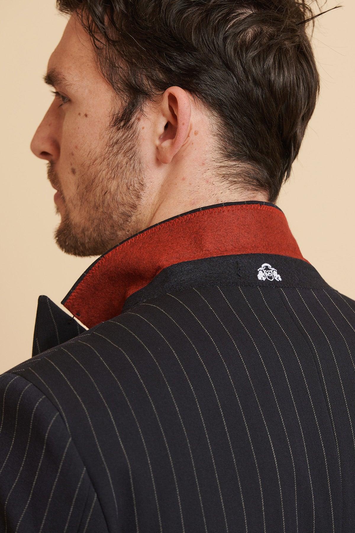 Close-up of a man's shoulder and head in the Marc Darcy ROCCO Navy Pinstripe Double Breasted Blazer, featuring a red collar and a small white embroidered crest on the back.