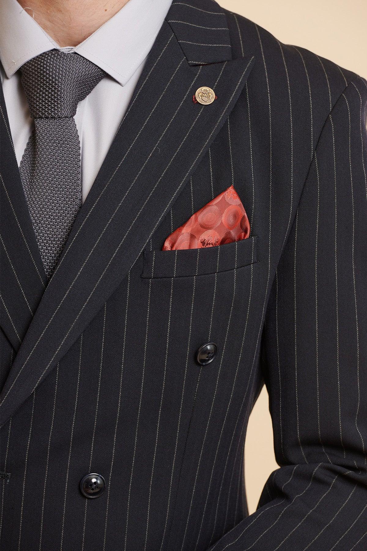 A person wearing the Marc Darcy ROCCO navy pinstripe double breasted blazer with a light gray dress shirt, textured gray tie, and an orange patterned pocket square in the breast pocket; only their upper torso is visible.