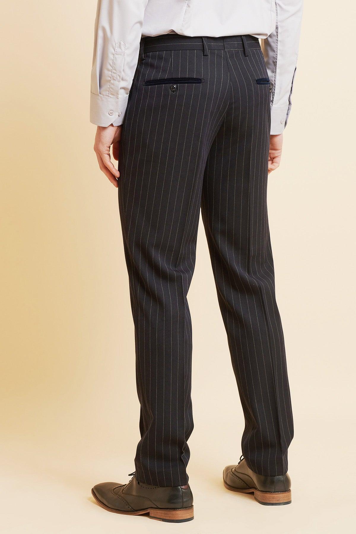 A person wears Marc Darcy's ROCCO Navy Pinstripe Trousers, a light gray dress shirt, and black dress shoes, standing on a beige background with their back to the camera.