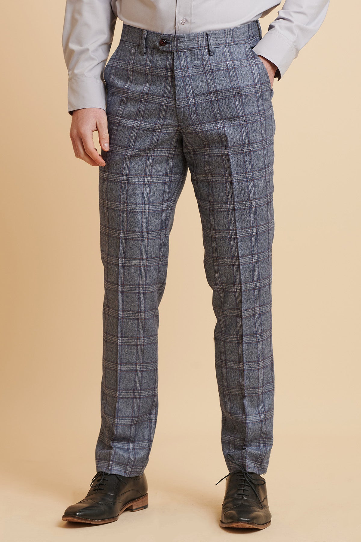 A person wearing marcdarcy ABBOTT Blue Tweed Check Trousers stands against a beige background, paired with a light gray dress shirt and black dress shoes. The persons head and upper body are not visible.
