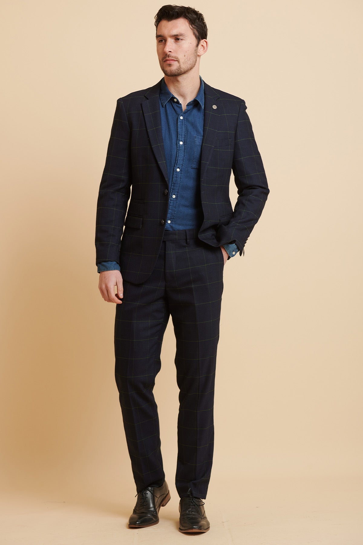 A man wears the Marc Darcy Everton Collection | Beto In EDINSON navy green check two-piece suit, standing with his hand in his pocket and looking to the left.