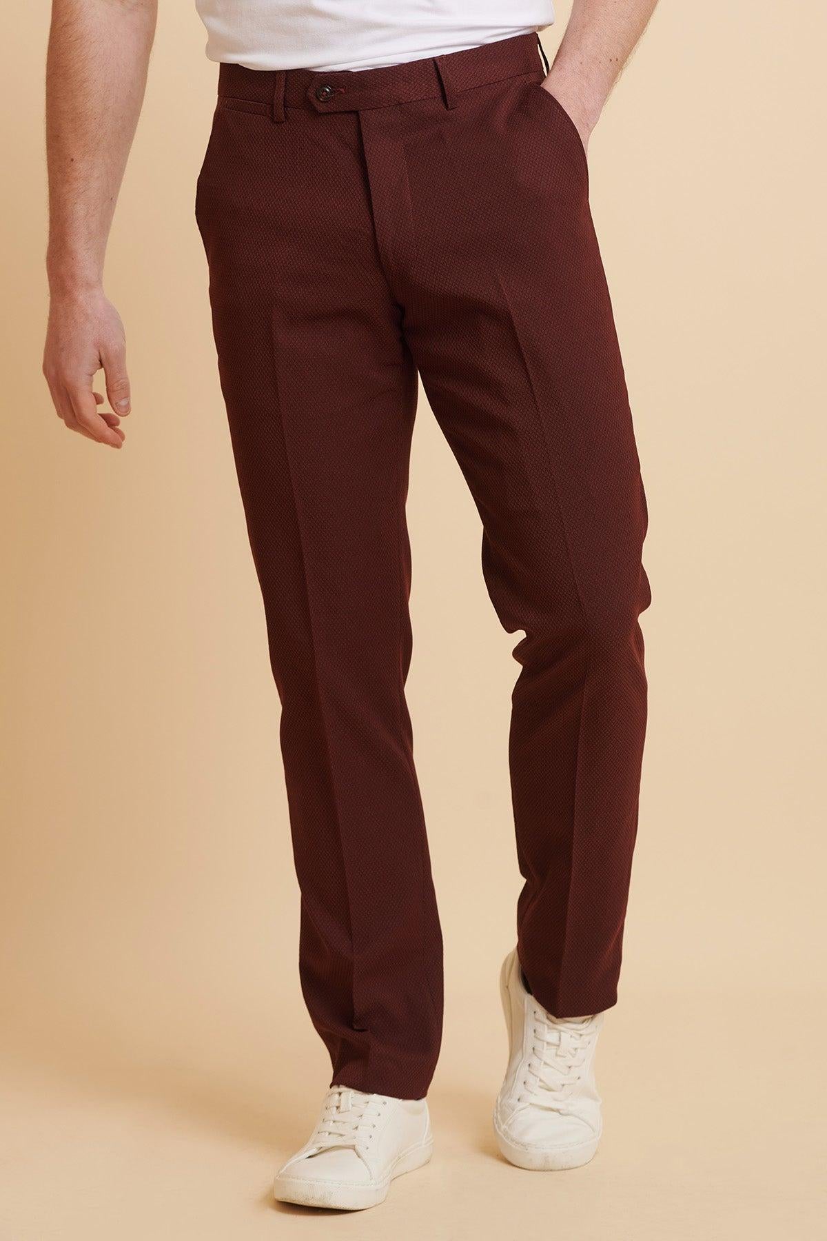 A man in the marcdarcy MAX Wine Two Piece Suit pairs it with white sneakers and a camouflage pocket square, with one hand casually placed in his pocket.