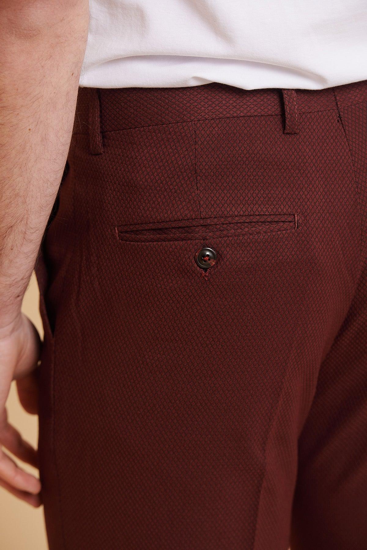 Close-up of a person wearing marcdarcy's MAX - Wine Two Piece Suit pants featuring a slim fit, textured diamond pattern, single buttoned back pocket, and paired with a white t-shirt.