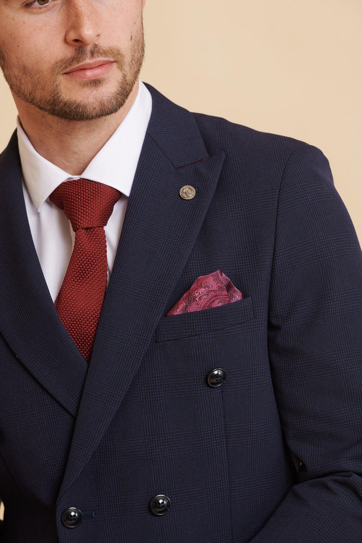 Man in a luxury formal look: Marc Darcy’s WHU Collection BROMLEY Navy Double Breasted Suit as worn by Jarrod Bowen, styled with a white shirt, red textured tie, and Prince of Wales check pocket square.