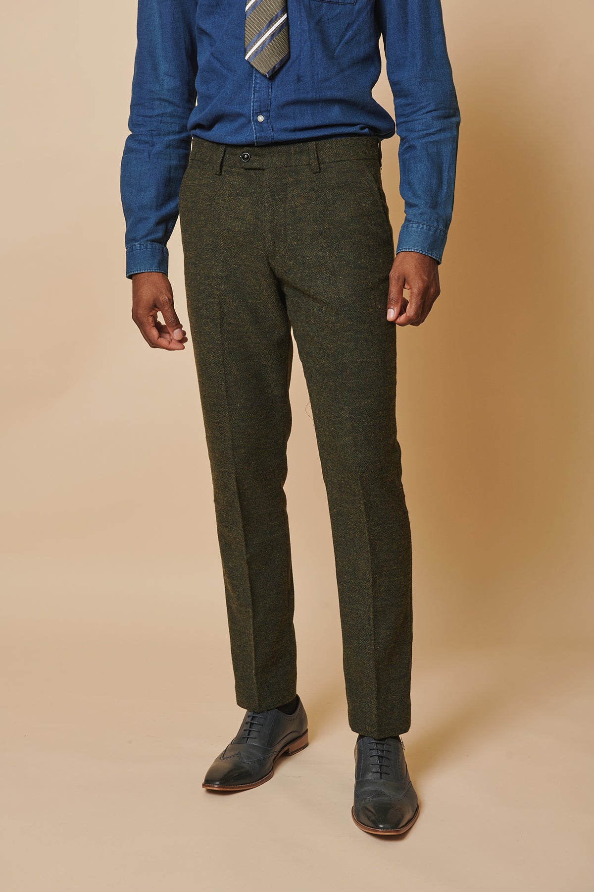 A man wears a denim shirt and tie with marcdarcy’s MARLOW Olive Green Tweed Trousers and dark leather dress shoes.