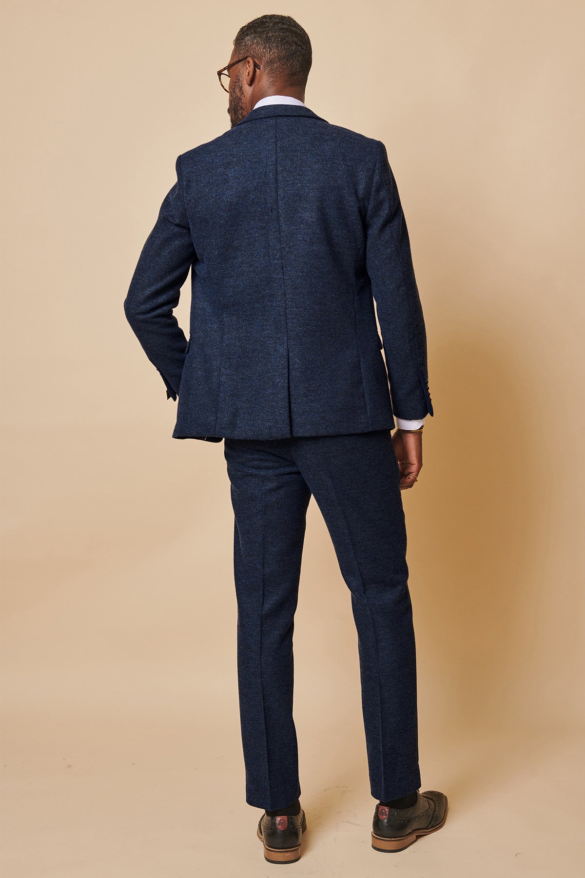A man in a MARLOW Navy Tweed Suit from the Leicester City F.C. Collection by marcdarcy, as worn by Wilfred Ndidi, poses against a light beige background.
