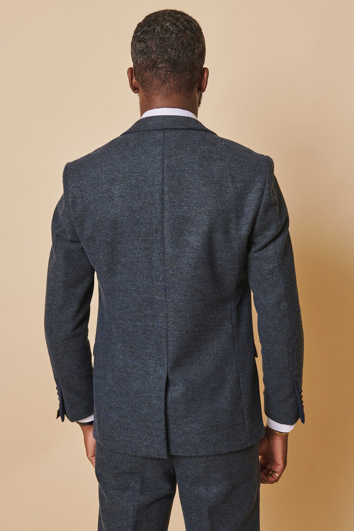 A man is seen from behind wearing the marcdarcy MARLOW Blue Tweed Blazer with matching textured trousers, standing against a plain beige background.