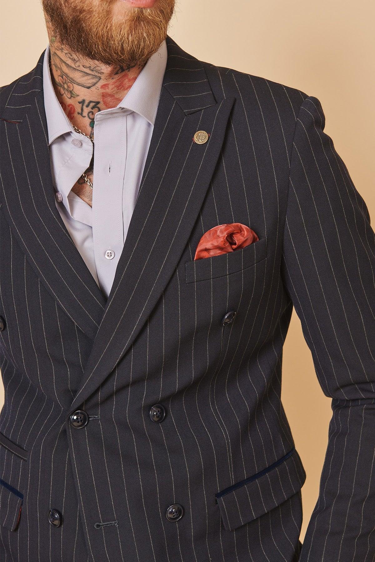 A man in the Marc Darcy Cardiff City F.C. Collection ROCCO navy double-breasted suit, worn by Ryan Wintle, paired with a light lilac shirt, gold lapel pin, and rust pocket square.