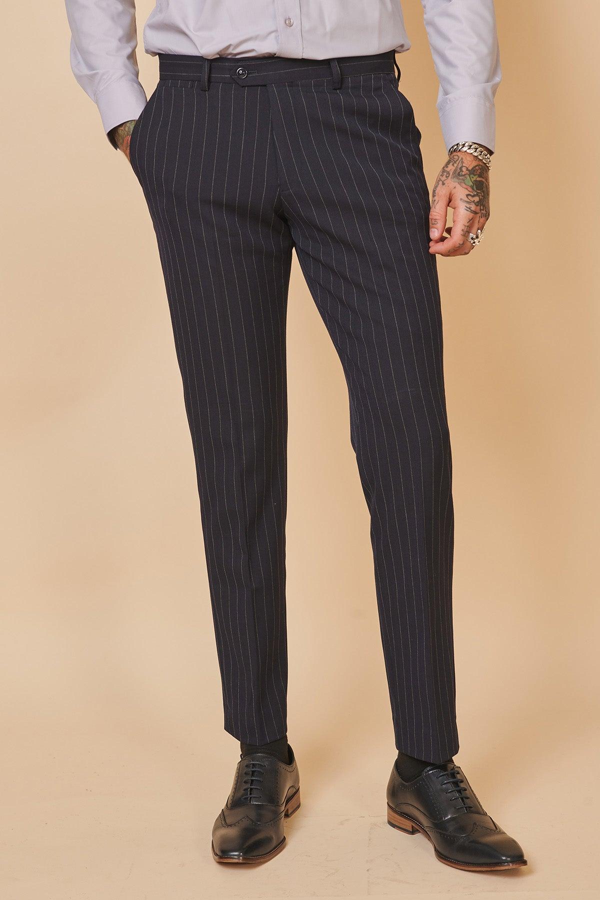 A person dressed in the Marc Darcy Everton Collection Jordan Pickford ROCCO Navy Pinstripe Double Breasted Two Piece Suit, paired with a light collared shirt and black oxford shoes.