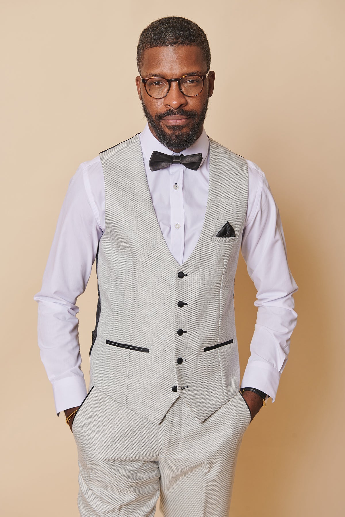 Ashley Young models the marcdarcy Everton Collection SPENCER Stone Tux Lapel Suit—slim fit, light grey vest, white shirt, and black bow tie—standing confidently with hands in his pockets.