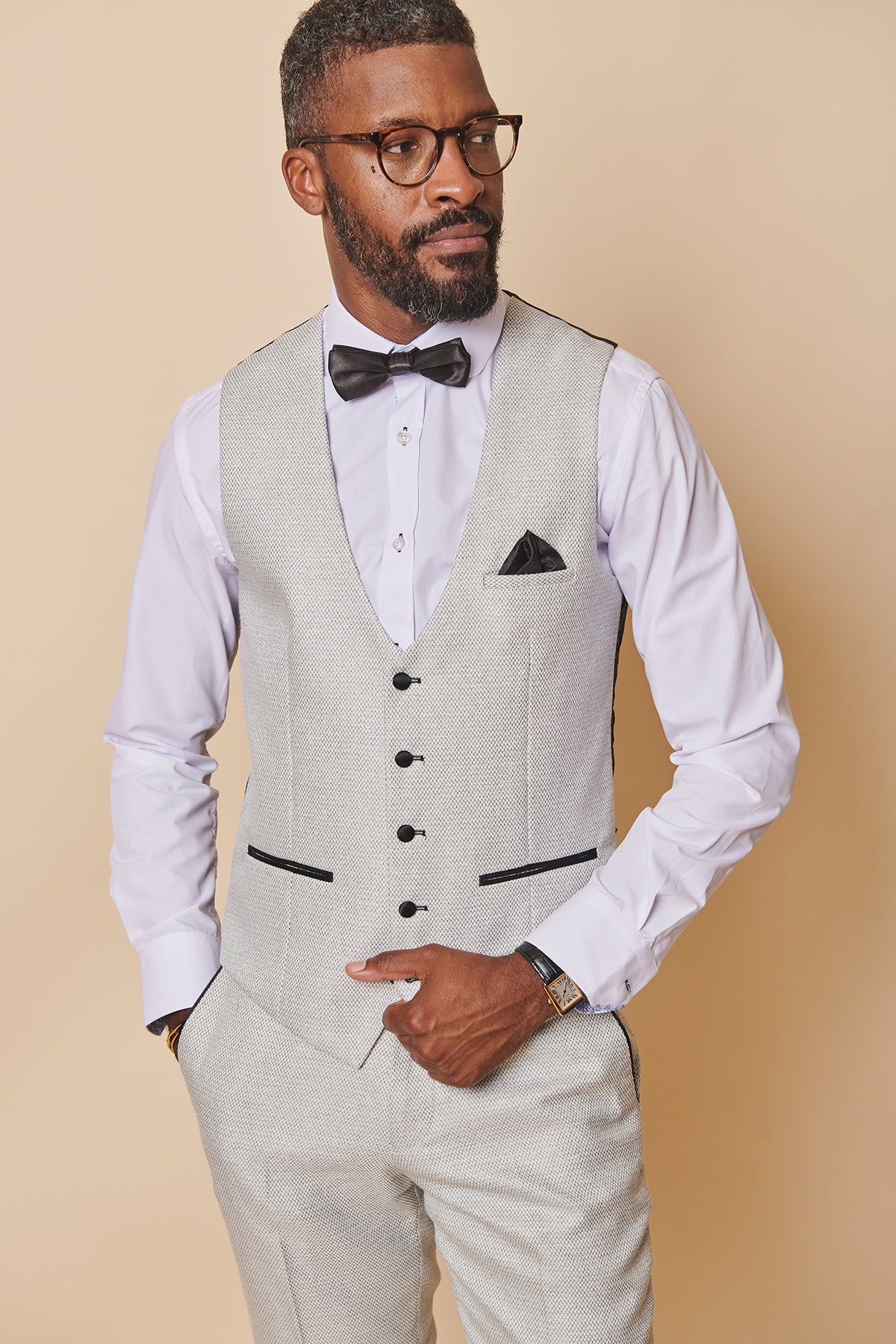 Man in marcdarcy’s SPENCER Stone Single Breasted Waistcoat, white shirt, black bowtie, and glasses. He also has a black pocket square.