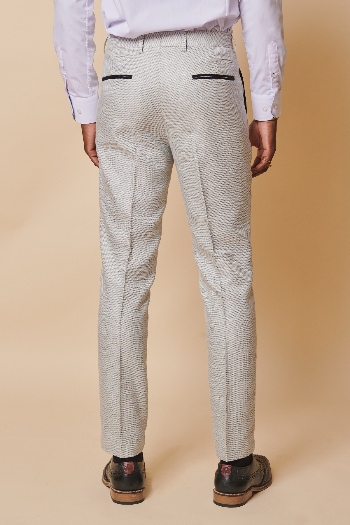 Rear view of a man in The Everton Collection's Ashley Young In SPENCER Stone Tux Lapel Suit by marcdarcy, paired with a white dress shirt and black wingtip shoes.