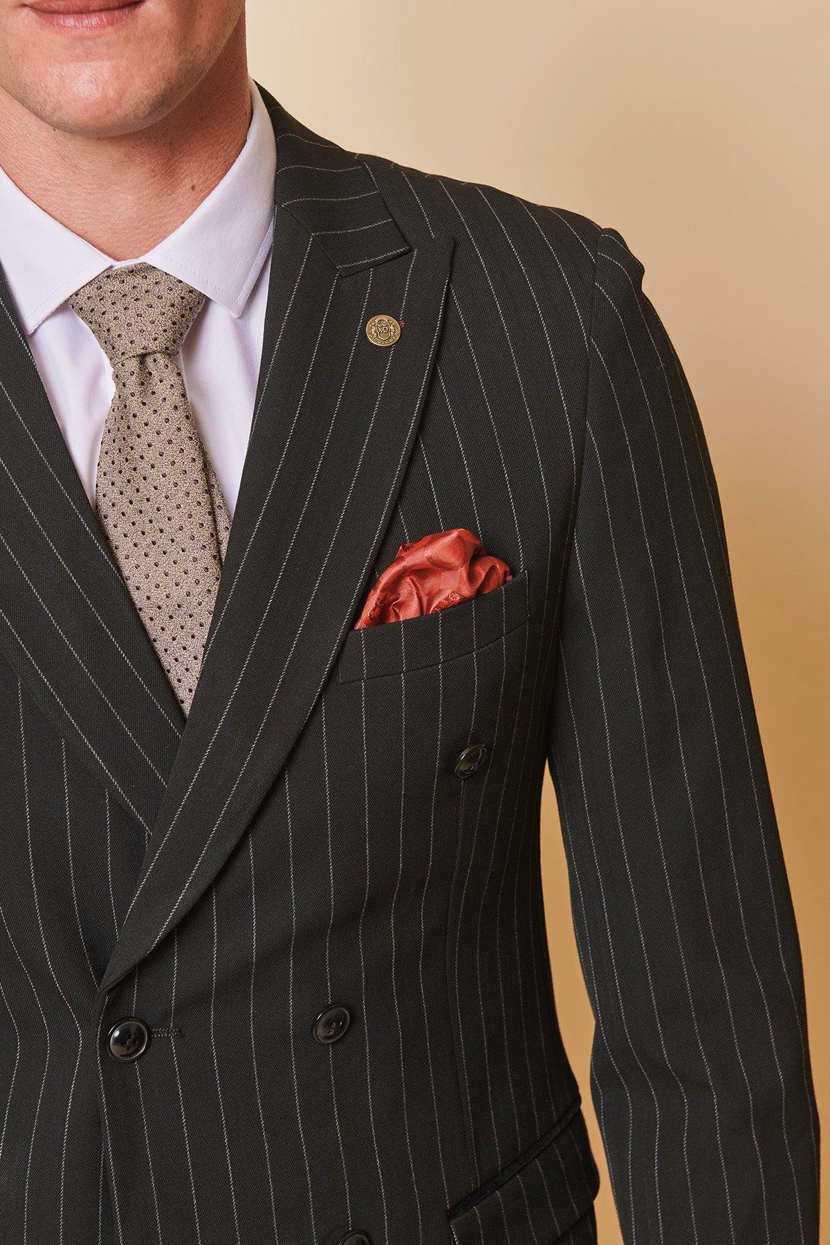 Coronation Street’s Mason Radcliffe (Luca Toolan) wears the Marc Darcy ROCCO Black Pinstripe Double Breasted Two Piece Suit, styled with a white shirt, beige patterned tie, and red pocket square against a neutral background.