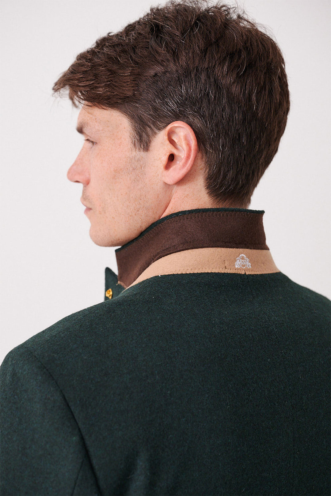 A man with short brown hair models the marcdarcy ARCHIE - Forest Tweed Three Piece Suit, featuring a slim fit and brown/beige collar with a small embroidered logo. Shown from the back and side, he looks to the left.