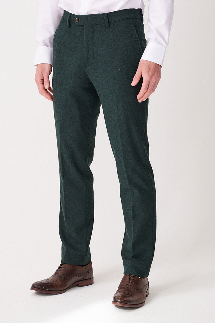 A person wears marcdarcy ARCHIE - Forest Tweed Trousers with a white shirt and brown dress shoes, standing against a plain light background. The image is cropped from the shoulders down.