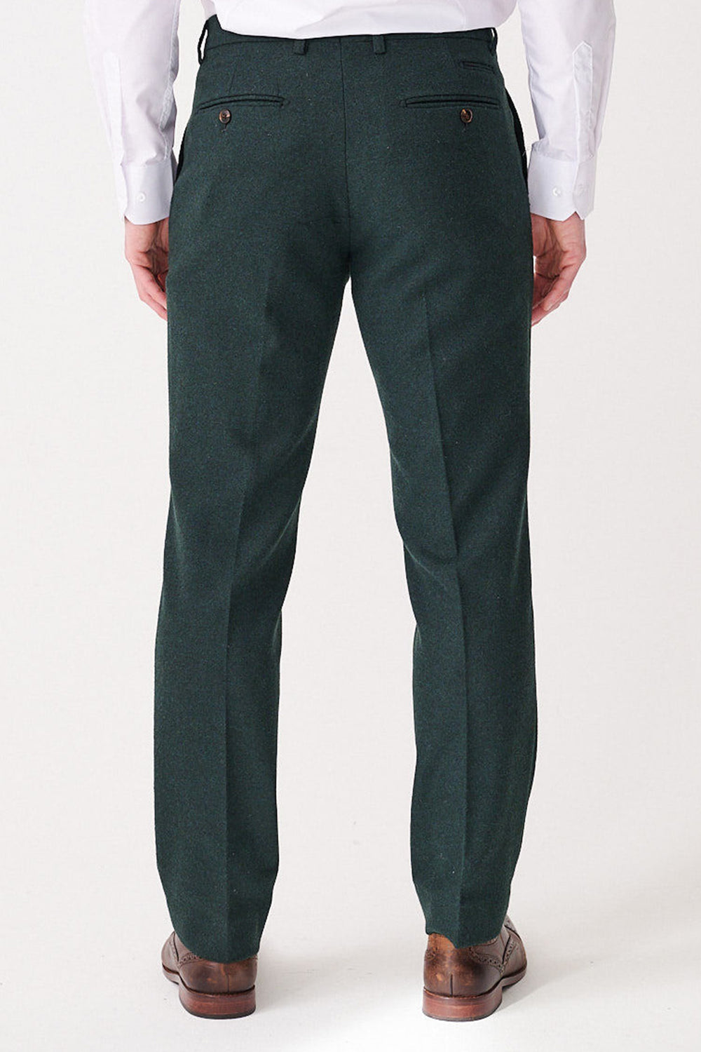 A man is seen from behind wearing marcdarcy ARCHIE - Forest Tweed Trousers, paired with a white shirt and brown dress shoes. The slim fit dark green trousers feature two buttoned back pockets.