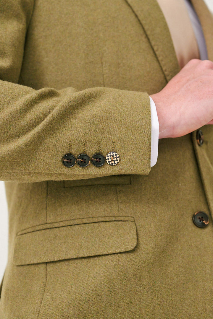 Close-up of a person wearing the marcdarcy ARCHIE Moss Tweed Three Piece Suit styled slim fit, with four sleeve buttons—one in gold and black pattern. A white shirt and beige tie complete the look.