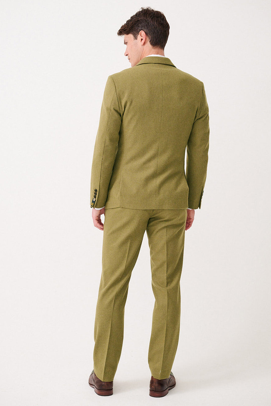 A man faces away from the camera, wearing the marcdarcy ARCHIE - Moss Tweed Three Piece Suit with matching pants and brown shoes, set against a plain white background.