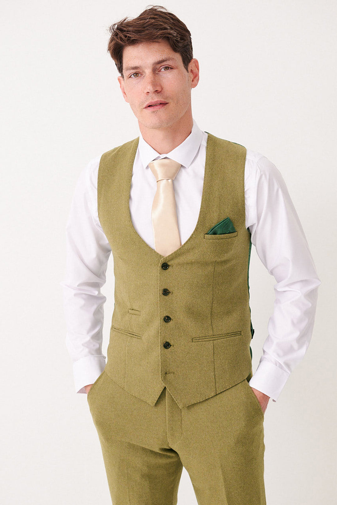 A man wearing a white dress shirt, light gold tie, and the Marc Darcy ARCHIE - Moss Tweed Waistcoat with matching trousers stands with hands in his pockets, facing the camera against a plain white background.