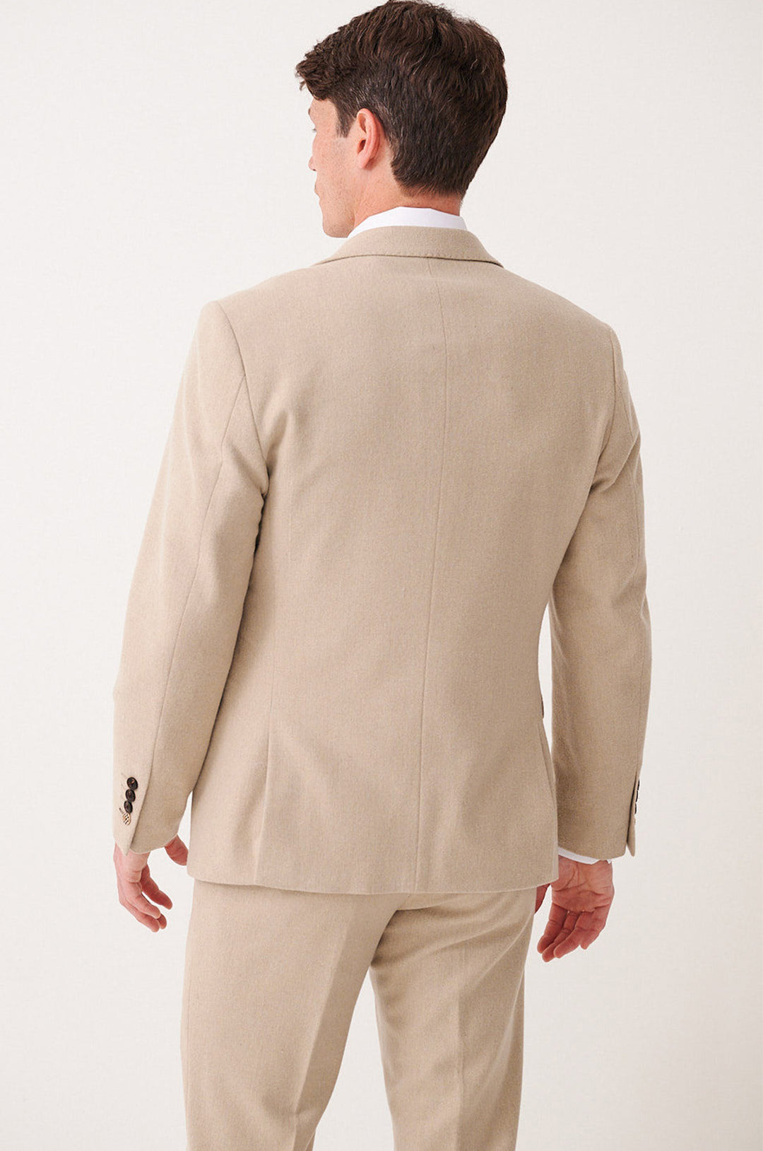 A man models the marcdarcy ARCHIE - Stone Tweed Blazer, standing with his back to the camera to reveal the suit jacket and matching trousers. His head is slightly turned left, arms relaxed at his sides.