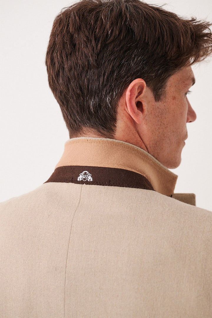 A man with brown hair is seen from behind wearing the marcdarcy ARCHIE Stone Tweed Three Piece Suit, featuring a beige slim fit coat with a turned-up collar accented by a brown trim and a small white embroidered logo.