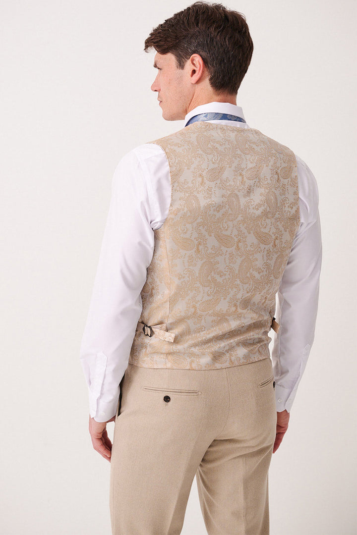 A man is shown from the back wearing the Marc Darcy ARCHIE - Stone Tweed Waistcoat, a slim-fit vest with adjustable side straps, paired with a white shirt and beige trousers. The background is plain and light.