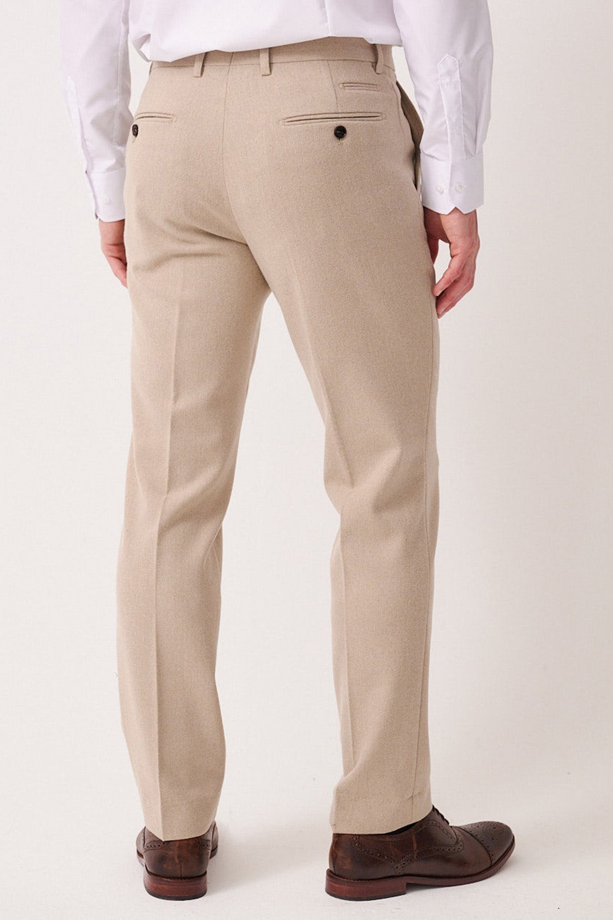 Man wearing marcdarcy ARCHIE - Stone Tweed Trousers, paired with a white shirt and brown wingtip shoes, shown from the back.