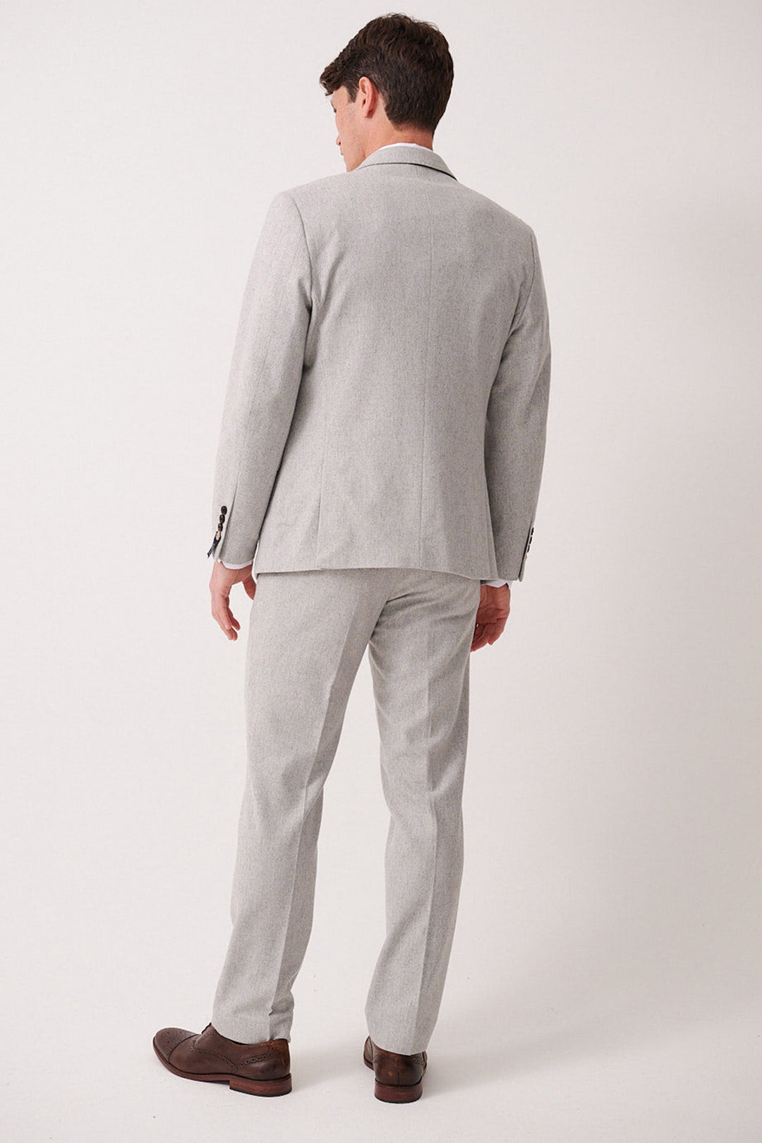 A man faces away from the camera, wearing the marcdarcy ARCHIE Silver Tweed Three Piece Suit with matching trousers and brown dress shoes against a plain white background.