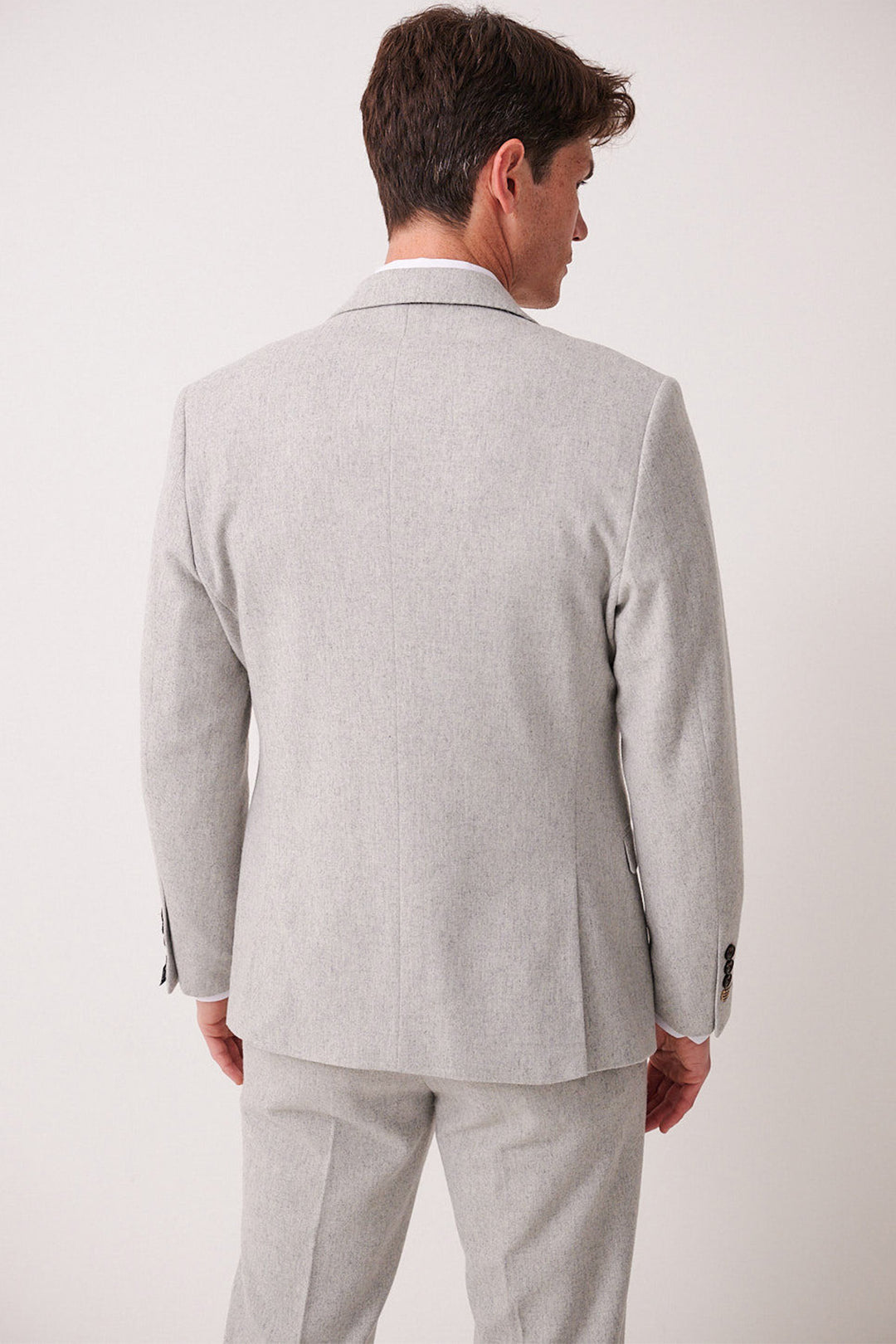 A man faces away from the camera, wearing the ARCHIE - Silver Tweed Blazer and matching pants by marcdarcy, set against a plain white background.