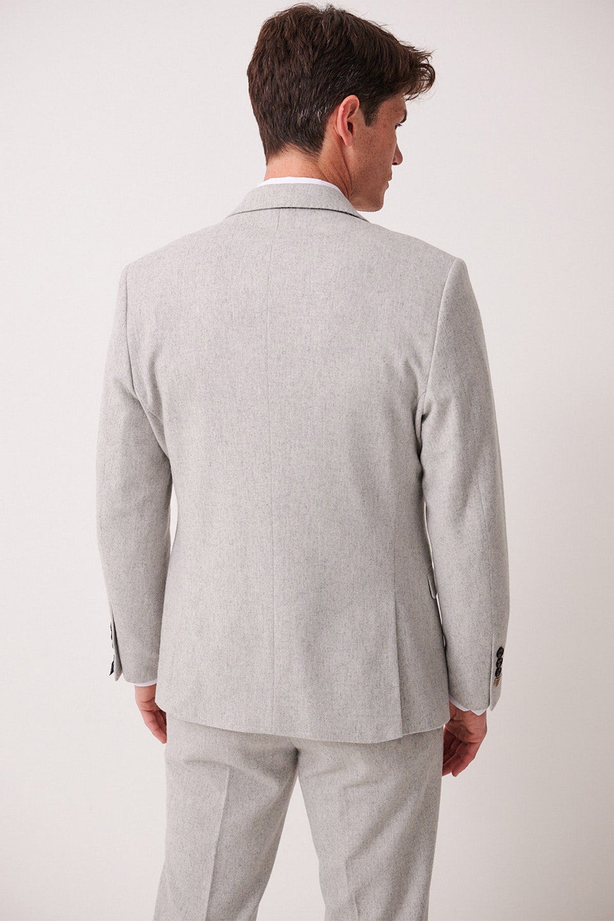 A man faces away from the camera, wearing the ARCHIE - Silver Tweed Blazer and matching pants by marcdarcy, set against a plain white background.