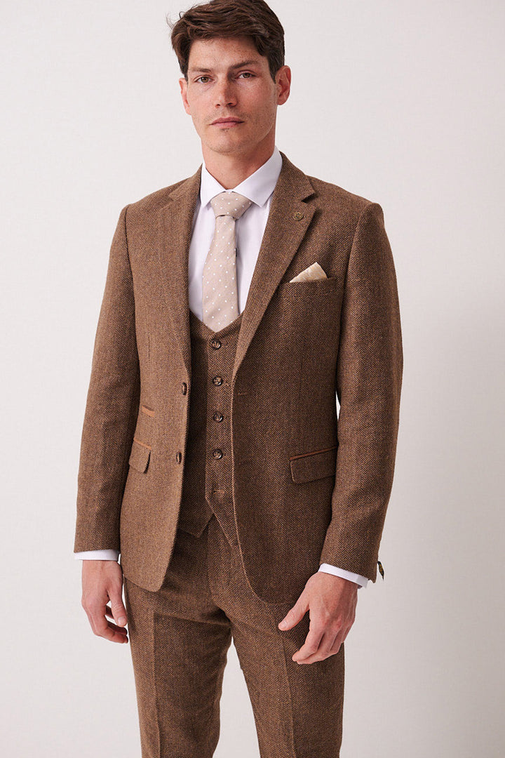 A man in a marcdarcy DEAN Tan Tweed Blazer stands against a plain light background, wearing a white dress shirt and beige polka-dot tie, looking at the camera with a neutral expression.