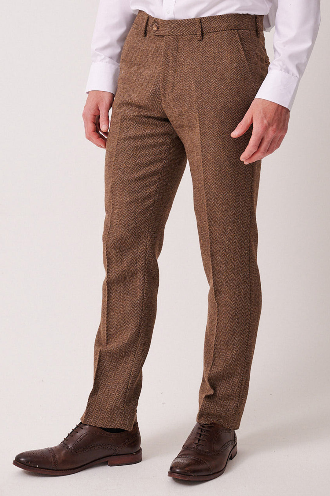 A man stands against a plain light background wearing marcdarcy's DEAN Tan Tweed Trousers, a white dress shirt, and brown leather dress shoes. His hands are relaxed at his sides.
