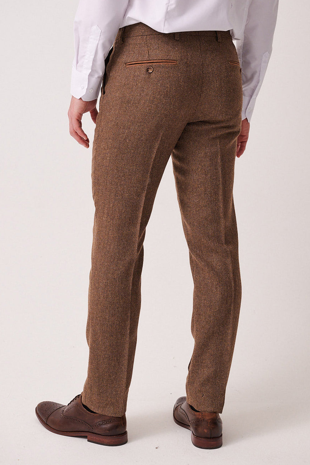 A person is seen from the back wearing marcdarcy's DEAN - Tan Tweed Trousers in a brown Prince of Wales check, paired with a white shirt and brown dress shoes, against a plain light background.