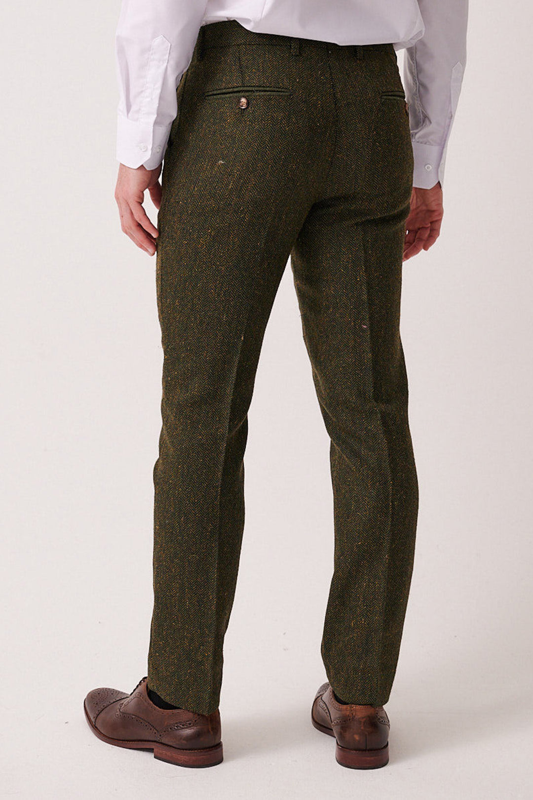 A man wears marcdarcy DEAN Olive Tweed Trousers with brown brogues and a white shirt. The back of the slim fit trousers is visible.