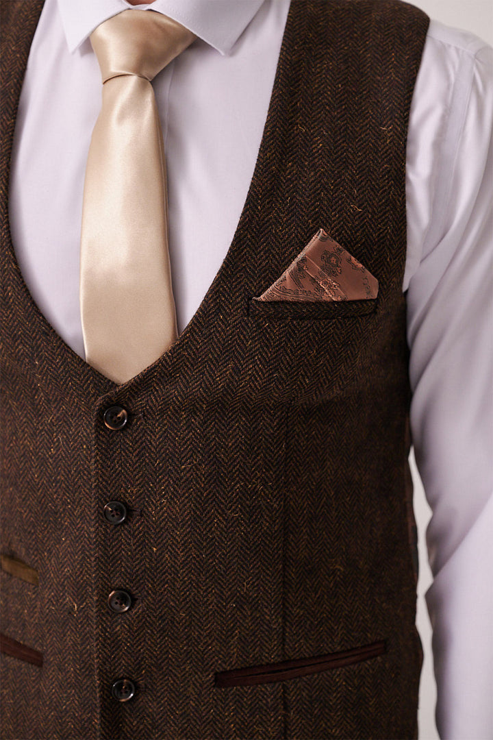 Close-up of a person wearing the marcdarcy DEAN Brown Tweed Three Piece Suit vest over a white shirt, styled with a shiny beige satin tie and a brown patterned pocket square.