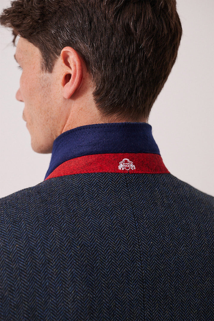 A man seen from behind wears the marcdarcy DEAN Blue Tweed Three Piece Suit, featuring a slim fit dark textured blazer with a red and blue collar lining and a small white embroidered logo at the back.