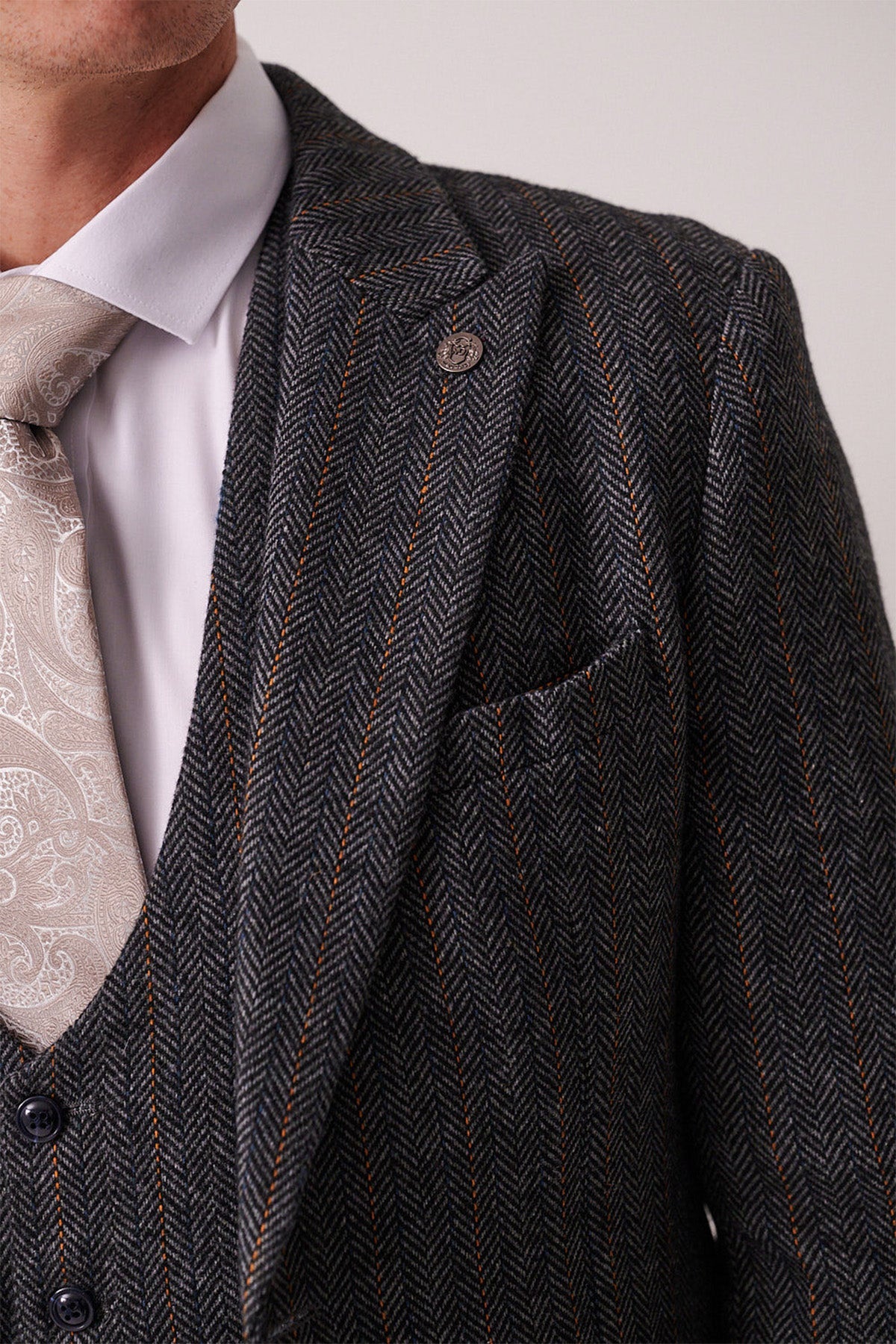 Close-up of a person wearing the marcdarcy DOMINIC Blue Grey Tweed Blazer, paired with a white dress shirt and a light beige paisley tie. Only the lower face and upper torso are visible.