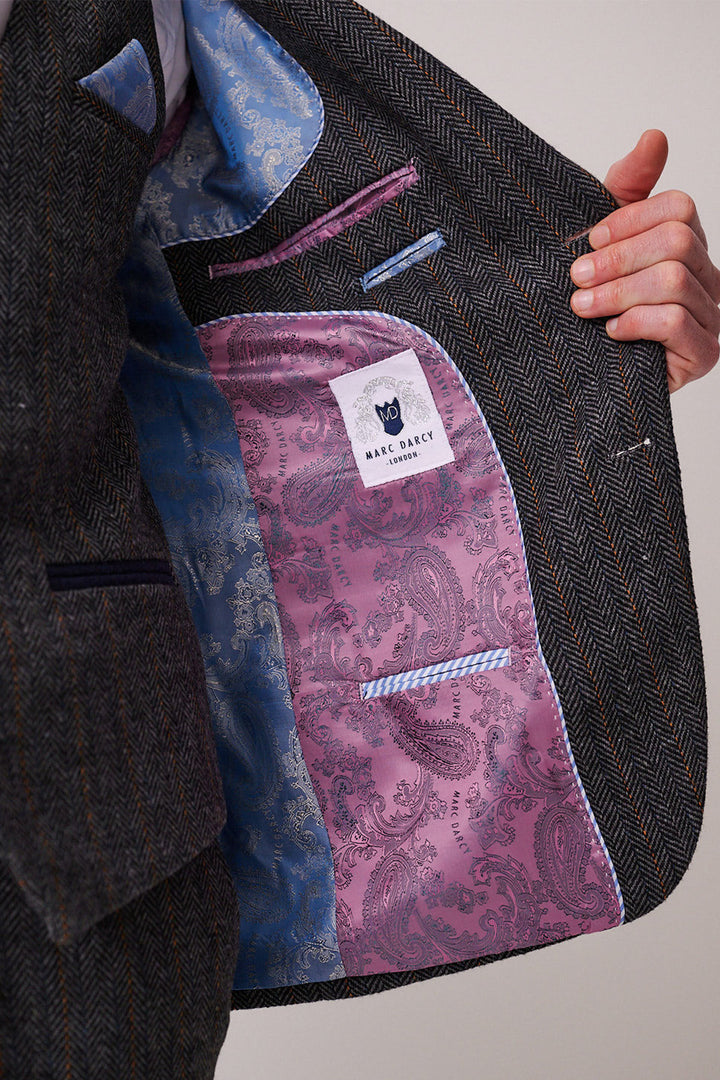 A person holds open a marcdarcy DOMINIC Blue Grey Tweed Three Piece Suit jacket to reveal a pink and blue paisley-patterned lining, with a visible marcdarcy label sewn inside.