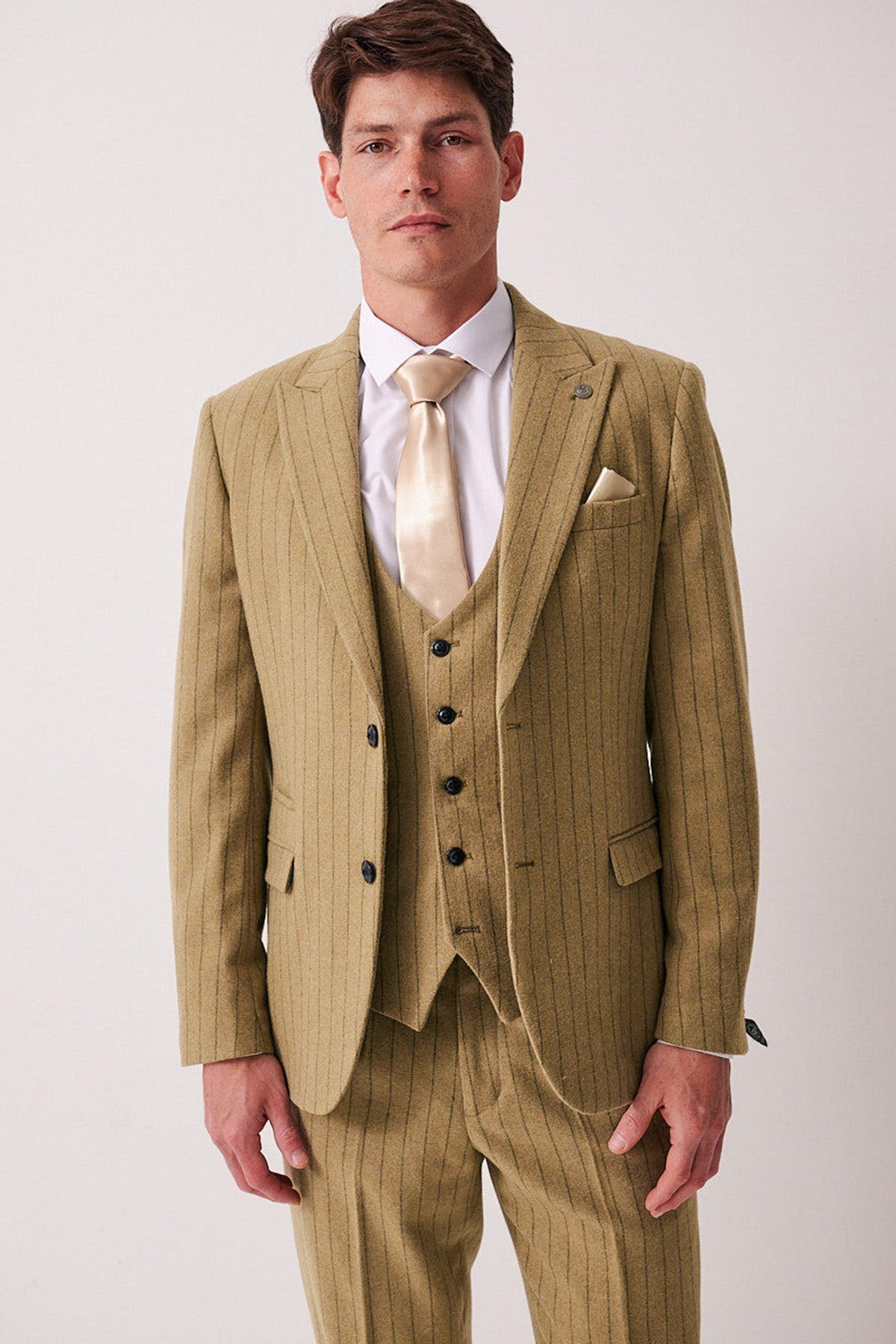 A man wearing the marcdarcy HANSON Moss Tweed Pinstripe Blazer with a matching vest, white dress shirt, cream satin tie, and pocket square stands against a plain light background, looking directly at the camera.