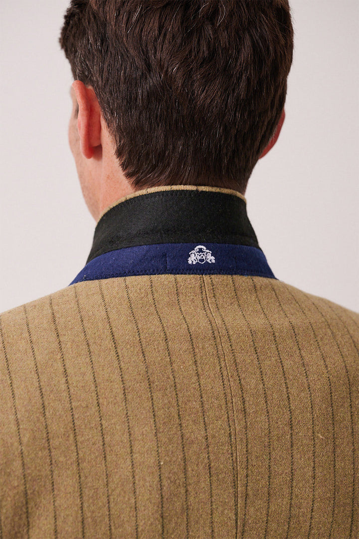 Back view of a person in the marcdarcy HANSON - Moss Tweed Pinstripe Three Piece Suit, featuring a brown pinstriped jacket with a black and blue collar, white embroidered detail on the back of the collar, and short brown hair visible.