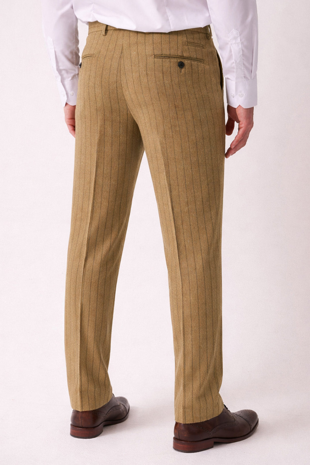 A person in the marcdarcy HANSON Moss Tweed Pinstripe Three Piece Suit stands with their back to the camera against a plain light background, wearing slim-fit tan pinstripe pants, a white shirt, and brown dress shoes.