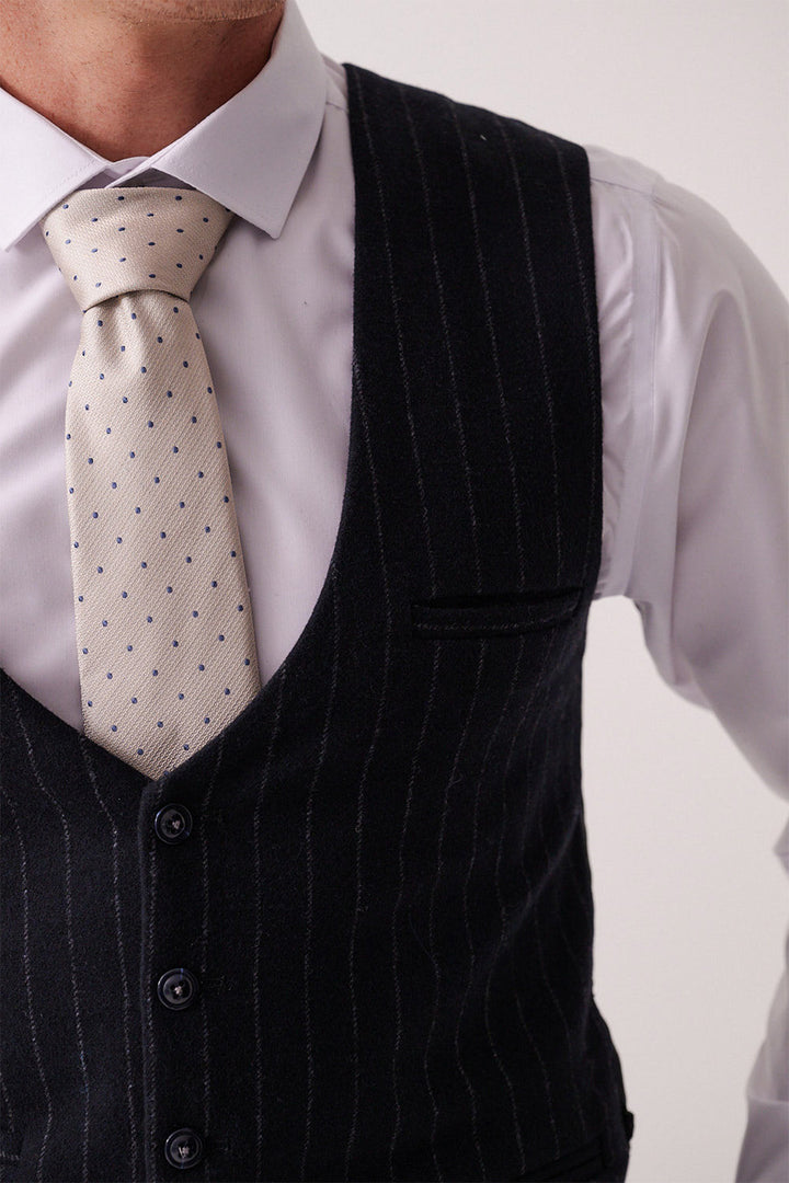 A man wears a slim fit light gray dress shirt, a tie with small blue dots, and the HANSON Navy Tweed Pinstripe Waistcoat by Marc Darcy. The image is cropped at the shoulders and mid-torso, showing only part of his face.