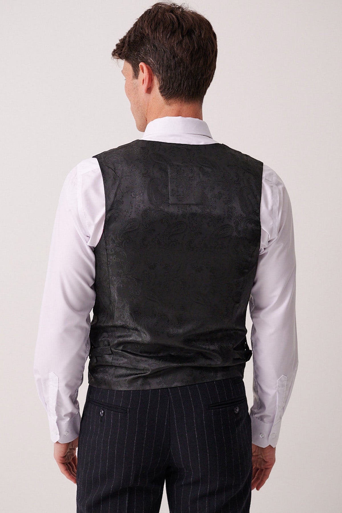 A man is shown from behind wearing the Marc Darcy HANSON Navy Tweed Pinstripe Waistcoat over a white dress shirt and dark pinstripe trousers, against a plain, neutral background.