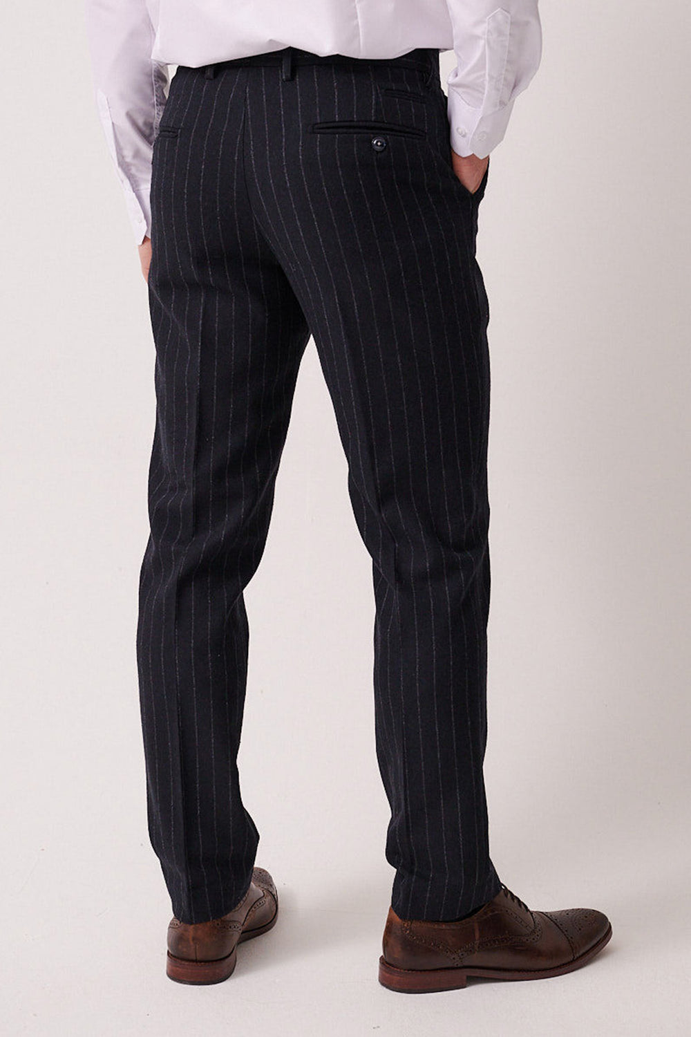 A person wearing a white dress shirt, marcdarcy HANSON Navy Tweed Pinstripe Trousers, and brown dress shoes stands with their back to the camera, hands in pockets.