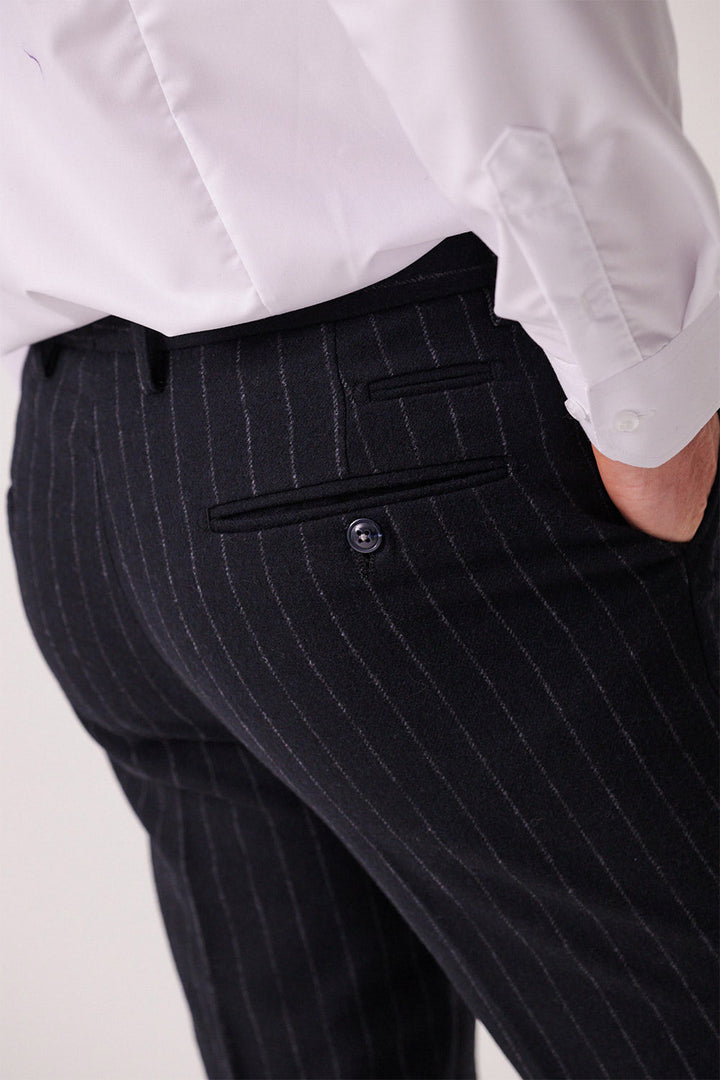 A person wears a white dress shirt and marcdarcy’s HANSON Navy Tweed Pinstripe Trousers, hand in the back pocket. The image spotlights the waist and upper legs, highlighting the textured fabric and button detail.