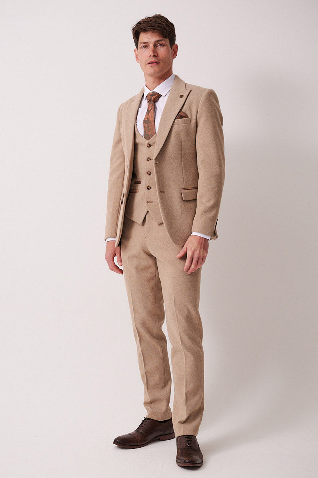 A man faces forward against a white background wearing the marcdarcy HAYDEN - Oak Crossweave Three Piece Suit, paired with a white shirt, brown patterned tie, pocket square, and dark brown dress shoes.