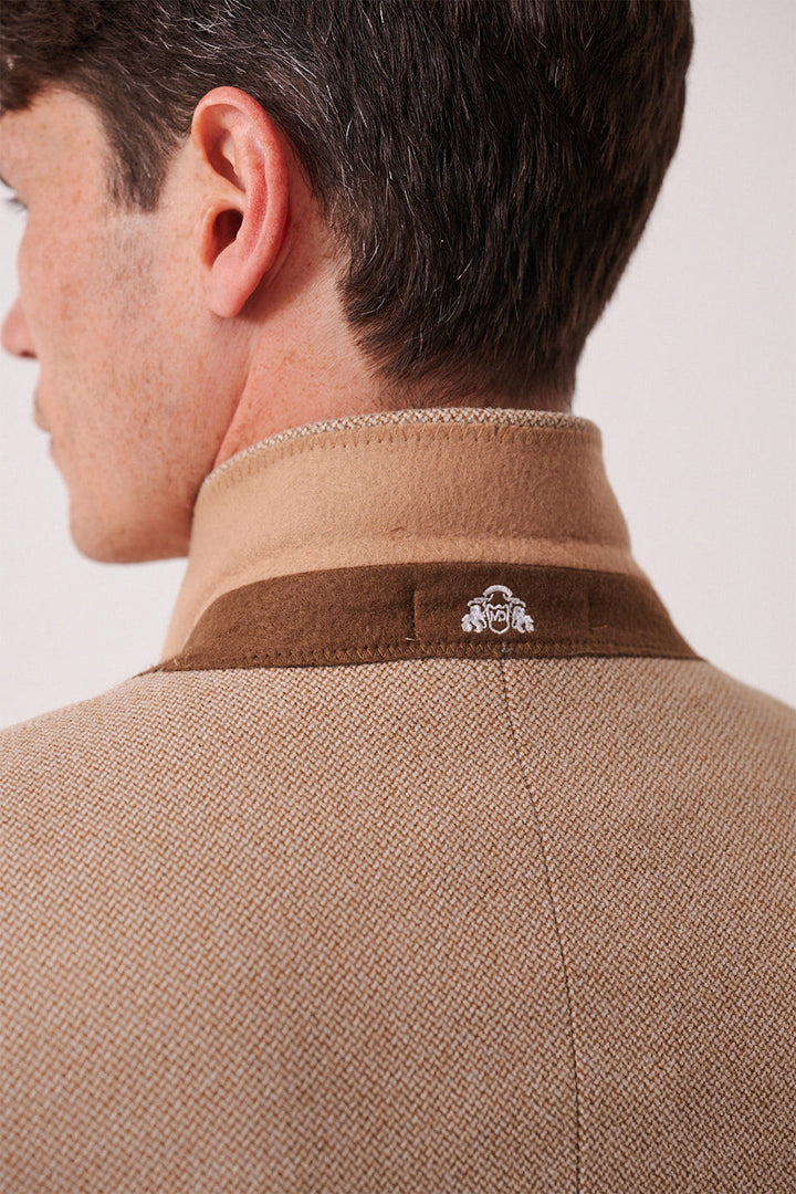 A close-up of a man's back and neck shows the marcdarcy HAYDEN - Oak Crossweave Three Piece Suit in tan and brown with a textured finish, standing collar, and a small white embroidered logo on the upper back.
