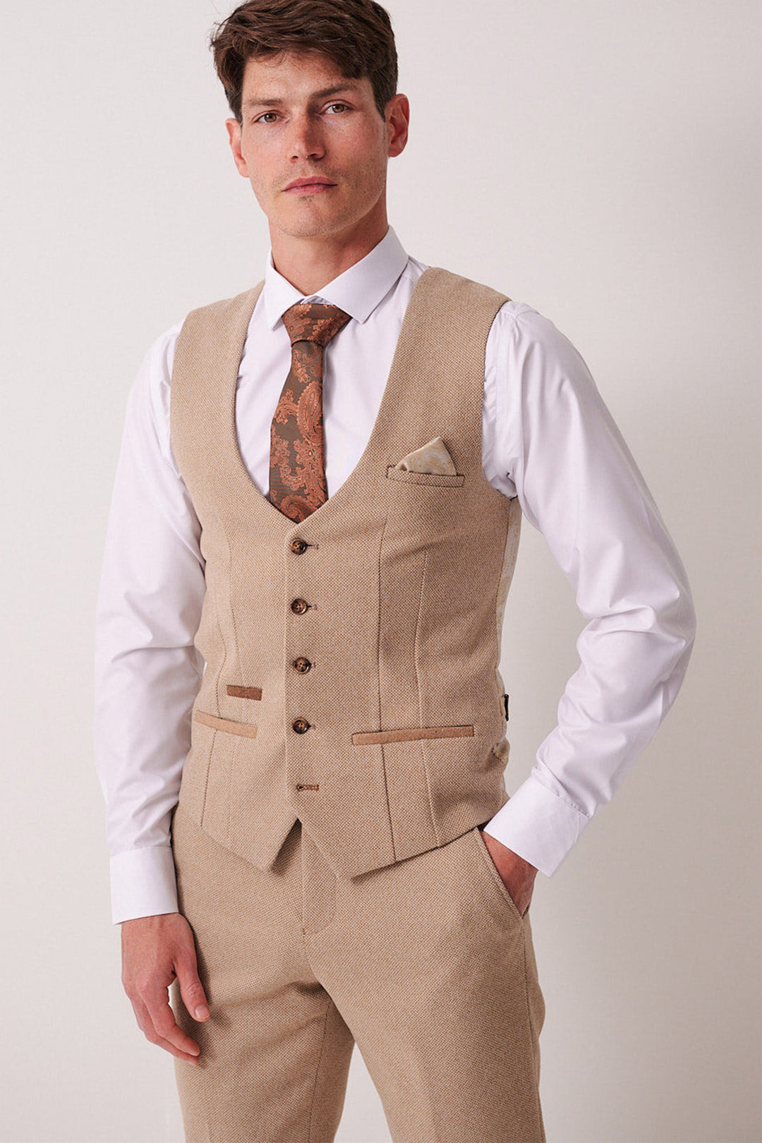 A man models the marcdarcy HAYDEN Oak Crossweave Three Piece Suit with vest, paired with a white shirt, brown patterned tie, and matching pocket square, standing against a plain light background.