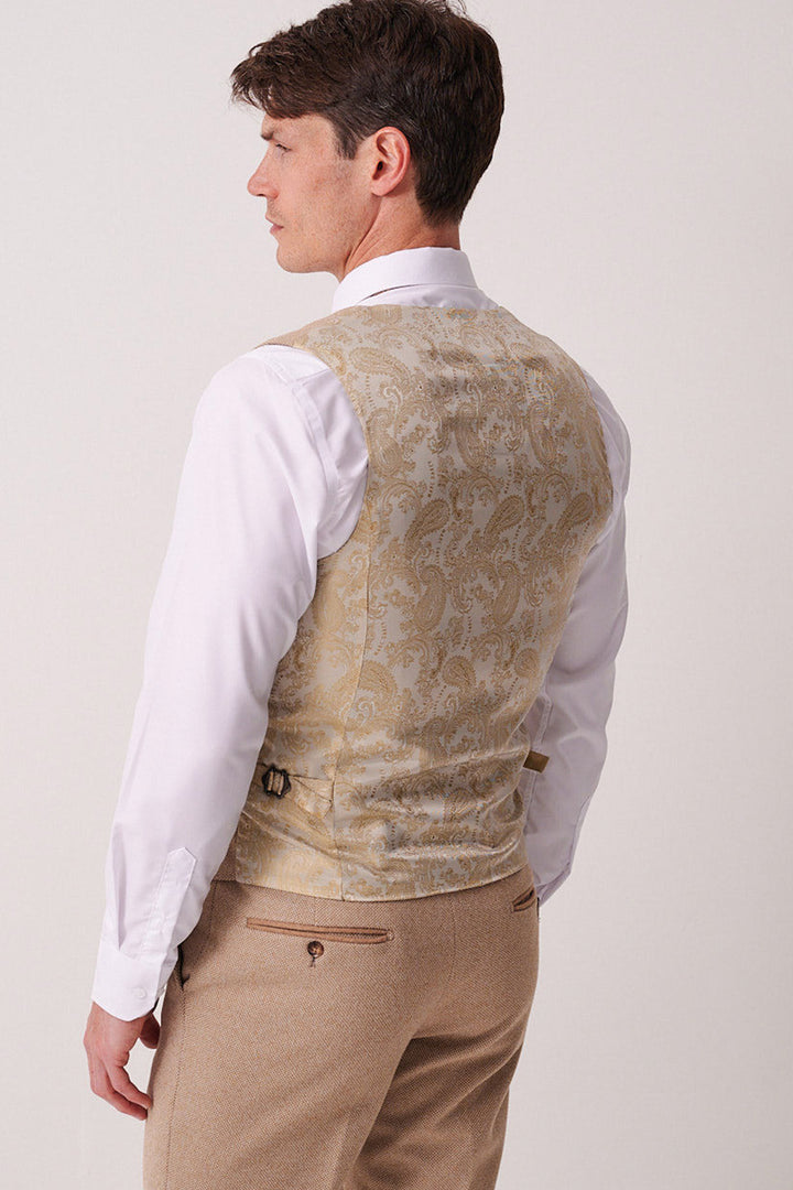A man faces away, displaying the back of his slim fit white shirt, Marc Darcy HAYDEN Oak Crossweave Waistcoat in light gold with pattern detail, and beige dress pants against a plain light background.